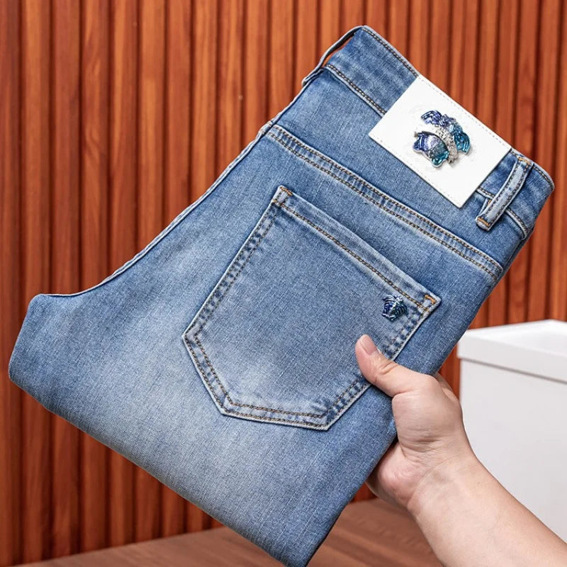 Hand holding a blue denim pouch with a decorative brooch against a wooden background